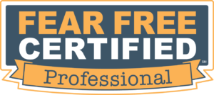 A rectangular logo with the text "FEAR FREE CERTIFIED" in white capital letters on a dark blue background, and "Professional Veterinarian" in black on an orange banner below. The text is surrounded by a white and orange border.